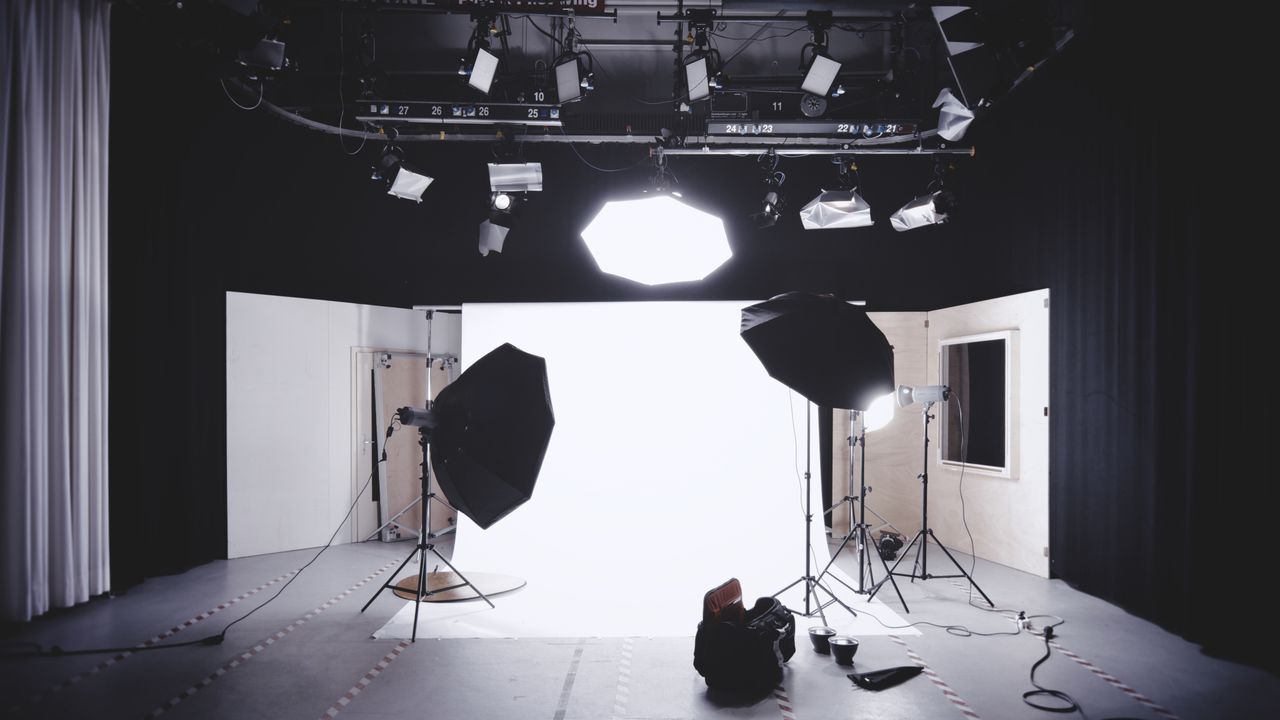 A well-equipped photography studio featuring lights, softboxes, and a white backdrop for professional shoots.